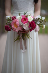 beautiful bouquet of pink and white peonies flowers in the hands of the bride in a white dress. Wedding day celebration.