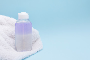 Cosmetic bottle with serum, gel, face cream with white towel on a blue background. Skin cosmetics, minimalism.