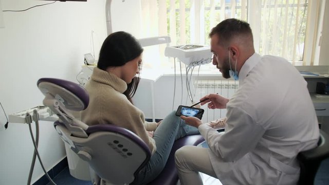 Dentist shows patient the situation of teeth. Doctor giving consultation to patient. Dentist shows x-ray image.