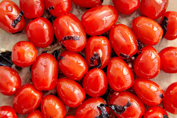 Top view of tomatoes with cut basil leaves on baking paper