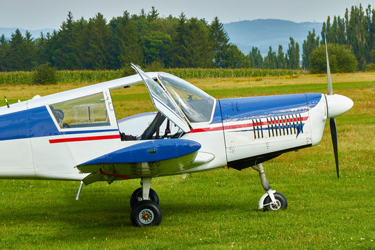 Side view of  Zlin Z-43 four-seat light airplane standing on a grass runway.  Low-wing monoplane.