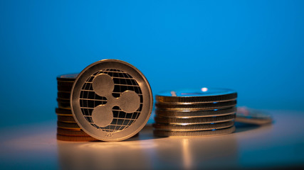 Gold Riple coin on blue background. Mining coin. Crypto trading