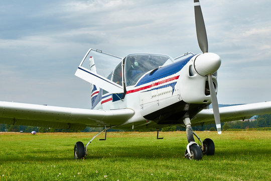 Front view of four-seat airplane Zlin Z-43 standing on a grass runway.  Low-wing monoplane.