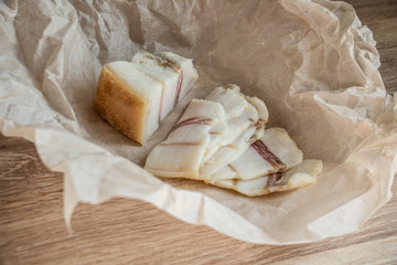 salted pork fat, sliced ​​in beautiful thin slices, national food of Ukrainians, delicious pork fat on a wooden table on parchment