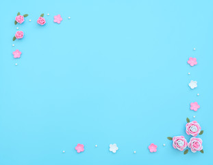 Pink and white flowers made of foamiran with green leaves and white beads on blue background. Mother day, Valentine day, Wedding, Birthday concept. Greeting or invitation card. Flat lay, copy space.