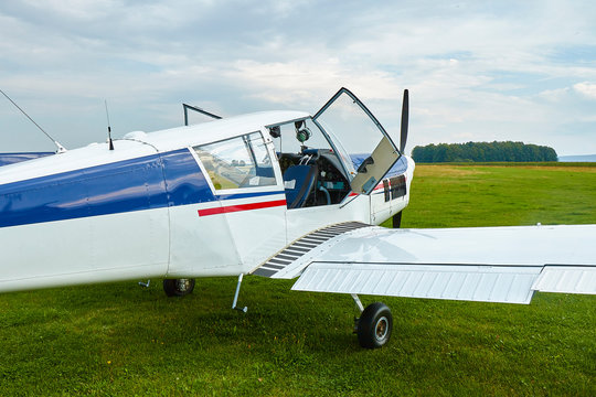 Closeup view of Zlin Z-43 four-seat airplane standing on a grass runway.  Low-wing monoplane.