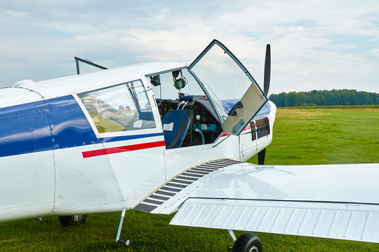 Closeup view of Zlin Z-43 four-seat airplane standing on a grass runway.  Low-wing monoplane.
