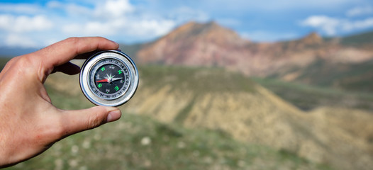 man hand compass and mountain