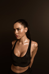 Fototapeta premium Sexy brunette sportswoman in sports top isolated on black