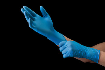 Doctor wearing a medical glove on hands isolated on black