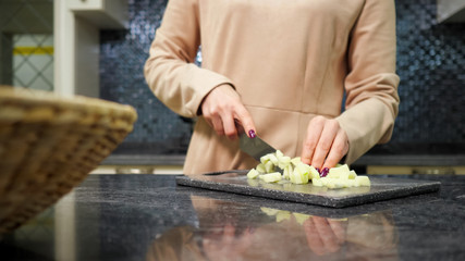 experienced housewife with nice manicure cuts vegetables cooking dish for lunch at kitchen marble table close view