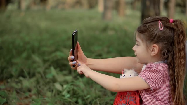 Little Girl Watching On Mobile Phone Screen With Mother.Happy Family Mom And Cute Little Kid Daughter Use Smart Phone And Take Selfie.Mother With Child Looking Cartoon.Family Make Video Call To Daddy.