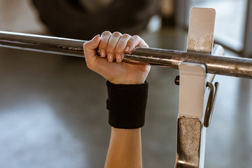 Fototapeta na wymiar Cropped view of sportswoman holding barbell in gym