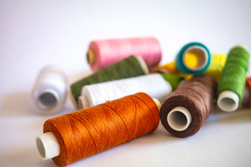 Multicolored bobbins with threads on an isolated white background close up