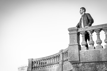 Lifestyle, portrait of a handsome young caucasian man with elegant leather suit looking towards the horizon