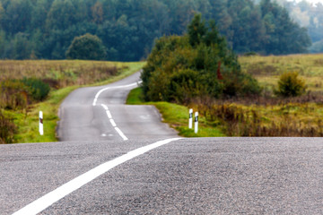 Fototapeta premium Narrow asphalt road through the hilly terrain on autumn day.