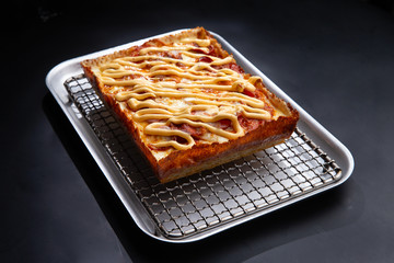 detroit pizza on an iron tray on a dark background. selective focus
