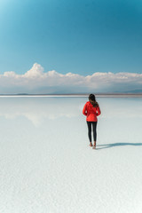 Travel. Woman. Salt Flats Uyuni Bolivia. Tourist girl on beautiful mirror reflection on blue sky and cloud. DRONE Shot in Salar de Uyuni salt flat. Holiday, love, adventure vacation honeymoon travel