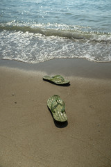 pair, two of men's beach slippers on the sand on the beach by the sea or ocean
