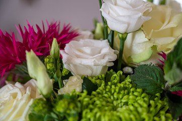 A closeup view of a bouquet with white roses, pink aster alpinus, and green spider mum flowers