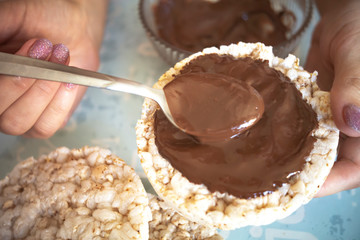 preparing a sweet dessert for Breakfast, smear a spoonful of chocolate on rice waffles
