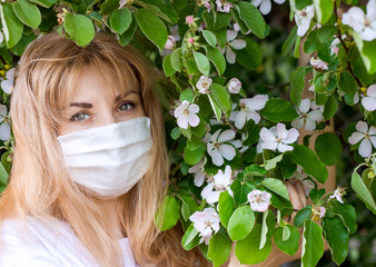 Girl in a medical mask near flowering quince tree. Protection against virus, flu. Spring allergy....