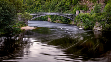 Fototapeta na wymiar long exposure of an old single span bridge over the river spey, Moray