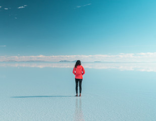 Travel. Woman. Salt Flats Uyuni Bolivia. Tourist girl on beautiful mirror reflection on blue sky and cloud. DRONE Shot in Salar de Uyuni salt flat. Holiday, love, adventure vacation honeymoon travel