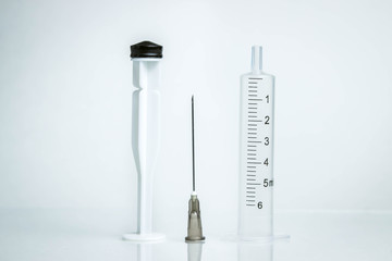 Medicine concept. Photo on a white background. Details of a disassembled syringe stand on a glass surface.
