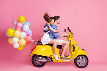 Fototapeta na wymiar Profile side view portrait of his he her she nice attractive cheerful cheery couple riding moped carrying bringing delivering air balls having fun weekend isolated on pink pastel color background
