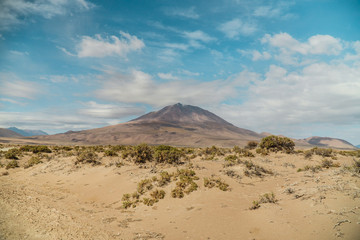 Dry, barren landscape mountain background.  Dramatic desert, snowcapped mountains wilderness. Mountain range view. Salt Flats of Uyuni, Bolivia. Copy space, blue sky, nature, hiking, and sand dust