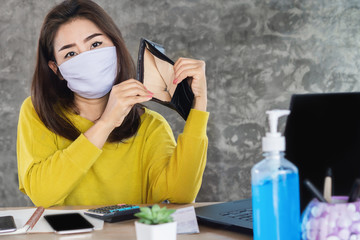 Fototapeta na wymiar poor Asian woman wearing protective mask hand open empty purse having financial problem during self-quarantine from covid-19 virus pandemic