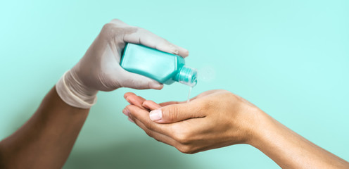 People cleaning hands with antiseptic alcohol gel - Female using disinfectant for preventing corona virus spreading - Hygiene and health care concept - Aquamarine background