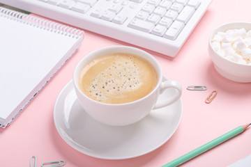 Woman office workplace with cup of coffee and pastel colorful stationery accessories on pink background. Top view