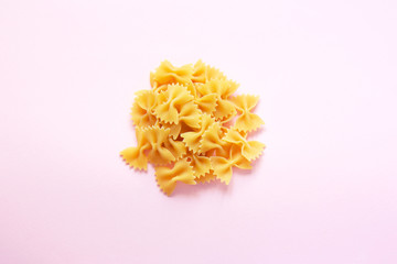 Raw farfalle pasta isolated on pink background. Selective focus