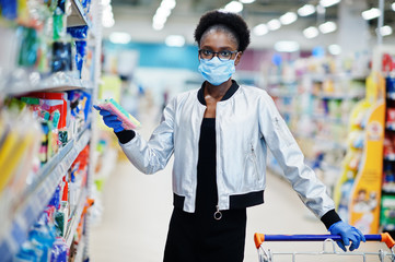 Fototapeta na wymiar African woman wearing disposable medical mask and gloves shopping in supermarket during coronavirus pandemia outbreak. Epidemic time.