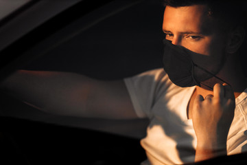 Man in protective medical mask  for protect himself from bacteria virus while planning to drive. Protective mask while quarantine, pandemic, covid 19, coronavirus, infection.