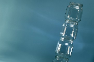 Vertical row of falling glass jars on a blue background.