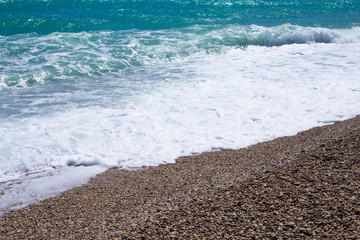 Sea waves background with small pebbles and foam of ocean water, place for text.