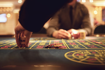 Close-up hand with chips on a roulette table.