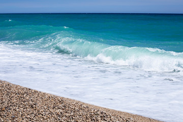 Sea waves background with small pebbles and foam of ocean water, place for text.