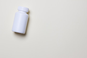 White plastic medical container for pills on left side of yellow background with copy space