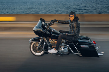 Motorcycle driver riding alone on asphalt motorway. Biker in the motion at the empty road