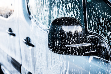 Washing car with soap. Close up clean car concept at car wash.