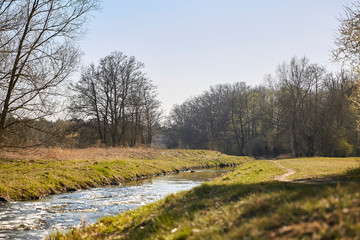 Fototapeta na wymiar Colorful landscape with a beautiful curved stream with reflections, green meadow, blue sky in spring in Brandenburg, Germany