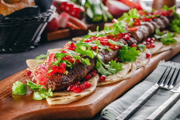 Lula Kebab on the wooden service plank with garnet and arabic bread