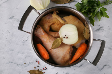 Cooking broth from homemade chicken with pepper and bay leaf in a pan on a marble background....