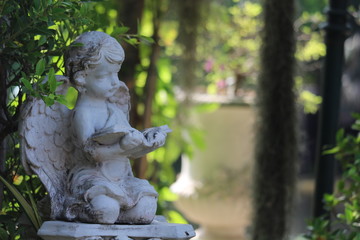 Little Cupid statue decorated in a natural garden