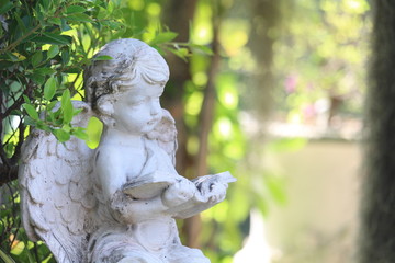 Little Cupid statue decorated in a natural garden