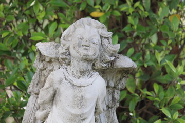 Fototapeta na wymiar Little Cupid statue decorated in a natural garden